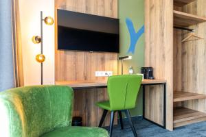 施泰尔Aiden by Best Western Stadtgut Hotel Steyr - FREE PARKING的客房设有书桌、电视和绿椅