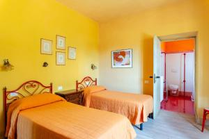 PopiglioTramonto al Rifugio Arcobaleno的黄色墙壁客房的两张床