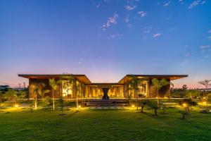 新德里StayVista's Anantam - Villa with Massive Outdoor Pool with Deck & Sprawling Lawn的前面有灯的大建筑
