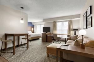 兀兰休斯敦伍德兰兹/市集大街原住客栈的酒店客房设有床和客厅。
