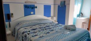 阿祖罗港Hotel VILLA ITALIA的一间卧室配有一张带蓝色和白色棉被的床