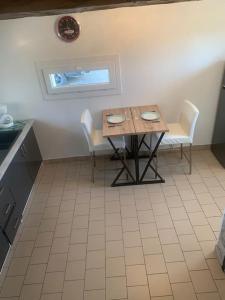 阿布维尔Duplex Le Chant des Oiseaux的厨房配有桌子和两把椅子,设有窗户。
