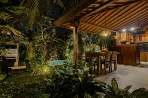 乌布Moringa Ubud Villa的凉棚下带桌椅的户外庭院