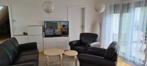维也纳TOP Apartments Kaiserebersdorf的客厅配有2把黑色椅子和电视