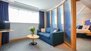 博尔顿Bolton Stadium Hotel的客厅配有蓝色的沙发和床。
