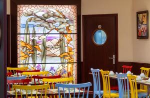 巴黎蒙帕纳斯总站酒店的一间用餐室,配有色彩缤纷的椅子和彩色玻璃窗