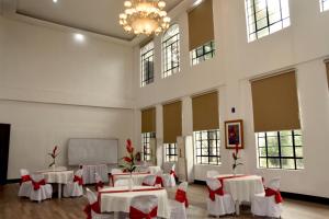 MamburaoIsla De Oro Hotel的大房间设有白色的桌子和椅子,还有红色的弓