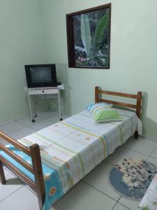 安格拉杜斯雷斯Apartamento em Chácara Aconchegante的一间卧室配有一张床和一张桌子及一台电视