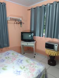 安格拉杜斯雷斯Apartamento em Chácara Aconchegante的一间卧室配有一张床、一台电视和一张书桌