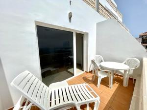 塔马达斯特Oceanfront apartment a few meters from the beach的阳台配有白色家具和桌椅。