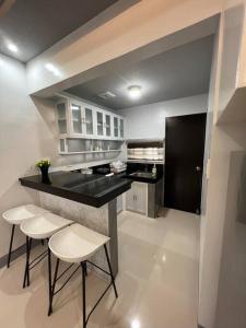 甲万那端Home in Cabanatuan city的厨房配有黑色柜台和白色椅子