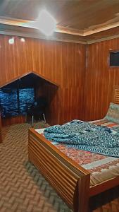 BālākotNorthern Huts And Riverview Restaurant的木镶板墙的客房内的一张床位