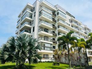 曼加拉蒂巴Apartamento Rio Marina Resort的一座高大的白色建筑,前面有棕榈树