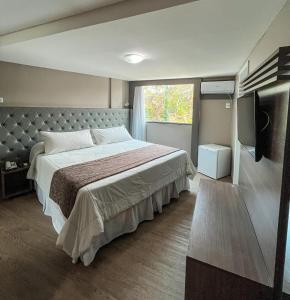 大坎皮纳大坎皮纳康福特村酒店的一间卧室配有一张大床和电视