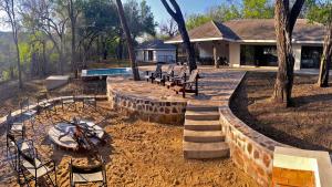 SimunyeMbuluzi Game Reserve的一个带椅子、火坑和房屋的后院