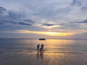 高兰班长滩旅馆的日落时站在海滩上的三人