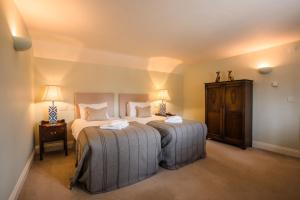 LoddonThe Loddon Swan的一间卧室配有两张床、一张桌子和两盏灯。