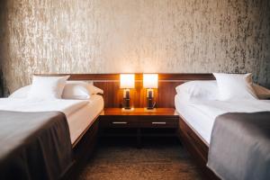 顺佩尔克优雅酒店的两间位于酒店客房的床,配有两盏灯