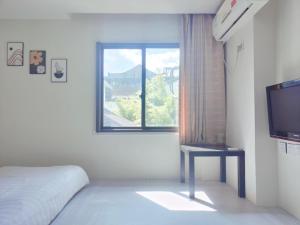 杭州望达斯旅舍的一间卧室设有一张床、一台电视和一个窗口。