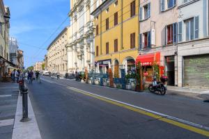 帕尔马Parma Parco Ducale Cozy Apartment的一条空荡荡荡的城市街道,街道上设有建筑和摩托车