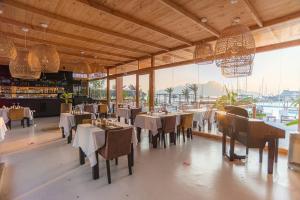 明德卢Mansa Marina Hotel的餐厅设有桌椅和大窗户。