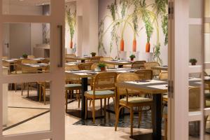 巴塞罗那加泰罗尼亚对角线中心酒店的餐厅墙上挂有桌椅和植物