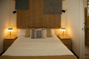 普拉森西亚HOTEL LOS ALAMOS BOUTIQUE的一间卧室配有一张带两盏灯的大型白色床。