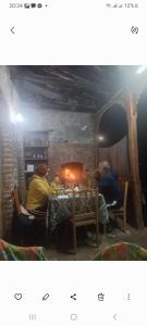 克瓦雷利Cottage and Gigo Papa's Wine Cellar的两个男人坐在壁炉前的桌子上