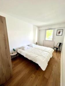 拉罗谢尔Superbe appartement avec parking的卧室设有一张白色大床和木地板
