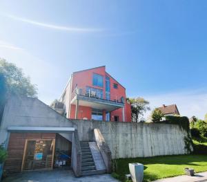 林茨Mountains and Lakes - Villa Gaumberg的水泥墙后面的红色建筑,有楼梯