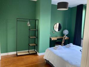 埃本埃迈尔Rue Haute by M&M 4 sterren bed en breakfast vlakbij Maastricht的一间卧室设有绿色的墙壁、一张床和一张书桌