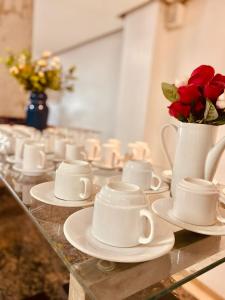 大坎普HOTEL CAMPO GRANDE的一组茶杯和碟子,放在桌子上,上面放着玫瑰