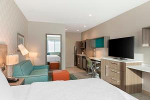 雷德兰兹Home2 Suites By Hilton Redlands的酒店客房配有一张床和一张书桌及一台电视