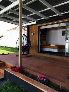 奥克兰Onehunga Garden Tinyhouse的木制甲板上配有床和阳台