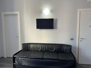罗马The Manzoni的墙上有电视的房间里一张黑色皮沙发