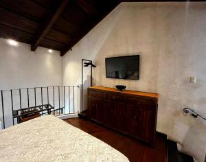 危地马拉安地瓜Boutique Villa in Antigua的一间卧室配有一张床,墙上配有电视