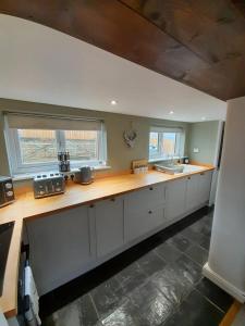沃明斯特Daisy Cottage的厨房配有白色橱柜和木制台面