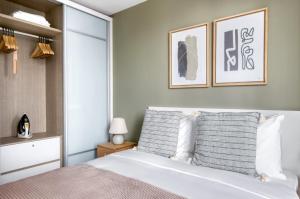 新加坡The Dapper Digs 2BR Apartment in Singapore的卧室配有一张白色大床,墙上挂有两张照片