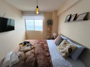 利马Nuevo apartamento con vista al mar a 15 min del aeropuerto的一间卧室配有一张带电视和桌子的床。