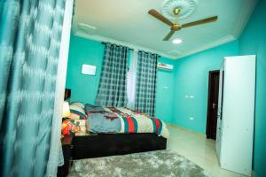 KasoaMatata Homes Airbnb的一间卧室设有蓝色的墙壁和一张带吊扇的床。