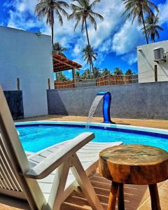 圣米格尔-杜斯米拉格里斯Villa Madu Milagres à 300 metros da praia的游泳池旁的椅子,带喷泉