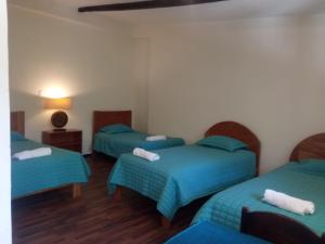 乌鲁班巴Casa de Mama Valle - Urubamba的带三张床和蓝色床单的客房