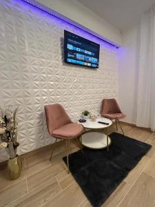 RoşuCozyStudio10的一间设有两把椅子、一张桌子和一台电视的房间