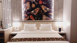 查亚普拉SIP Azana Hotel Jayapura的卧室配有一张大床,墙上挂有绘画作品