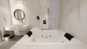 查亚普拉SIP Azana Hotel Jayapura的白色的浴室设有浴缸和水槽。