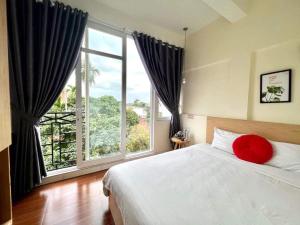 顺化Hue Four Seasons Hotel的一间卧室设有大窗户和一张带红色枕头的床