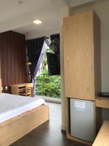 顺化Hue Four Seasons Hotel的一间卧室设有一张床、一台电视和一个窗口。