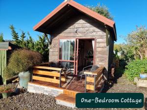 陶朗加Swiss-Kiwi Retreat A self-contained Appartment and a Tiny House option的小屋设有门廊,小木狗屋