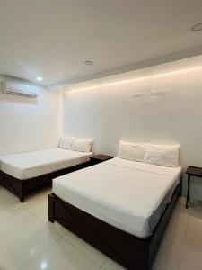 奥隆阿波Samba Bluewater Resort的配有白色墙壁的小客房内的两张床