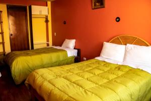 普诺ANDENES DEL TITICACA的橙色墙壁的酒店客房内的两张床
